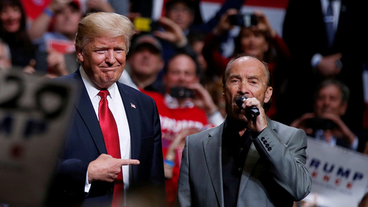 U.S. President Donald Trump (C) joins singer Lee Greenwood onstage as he sings 