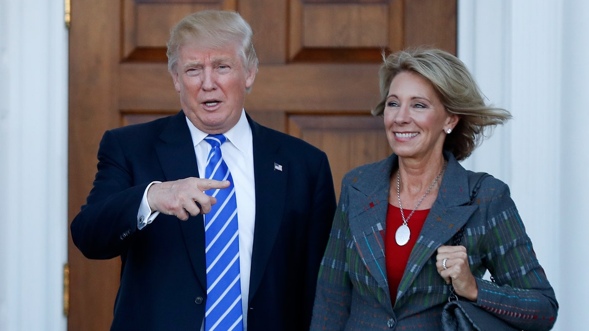 FILE - In this Nov. 19, 2016 file photo, President-elect Donald Trump and Betsy DeVos pose for photographs at Trump National Golf Club Bedminster clubhouse in Bedminster, N.J. Trump has chosen charter school advocate DeVos as Education Secretary in his administration. (AP Photo/Carolyn Kaster, File)