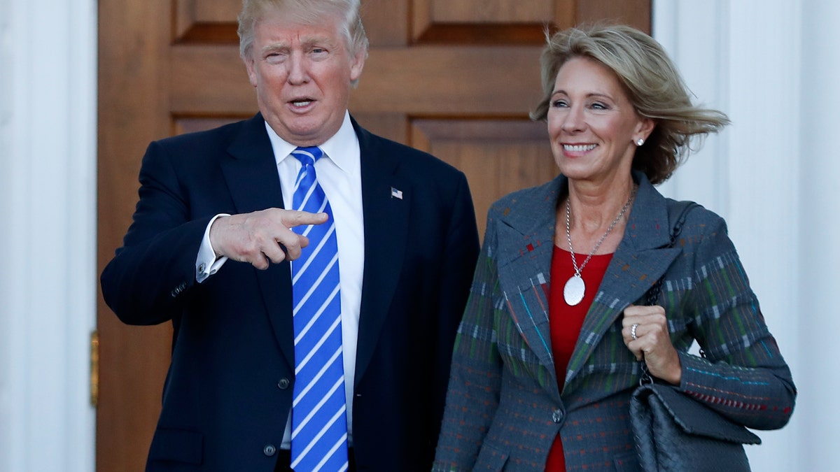 FILE - In this Nov. 19, 2016 file photo, President-elect Donald Trump and Betsy DeVos pose for photographs at Trump National Golf Club Bedminster clubhouse in Bedminster, N.J. Trump has chosen charter school advocate DeVos as Education Secretary in his administration. (AP Photo/Carolyn Kaster, File)