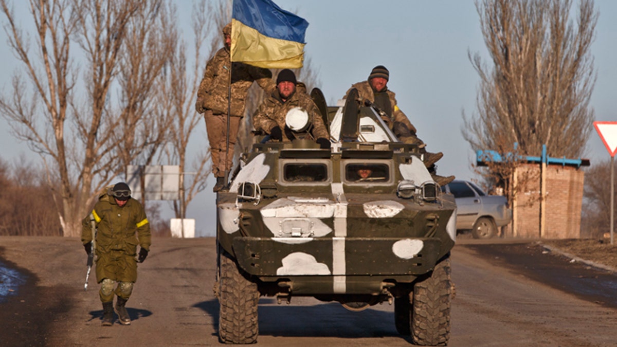 Ukrainian troops ride on an armored vehicle outside Artemivsk, Ukraine, while pulling out of Debaltseve, Wednesday, Feb. 18, 2015. After weeks of relentless fighting, the embattled Ukrainian rail hub of Debaltseve fell Wednesday to Russia-backed separatists, who hoisted a flag in triumph over the town. The Ukrainian president confirmed that he had ordered troops to pull out and the rebels reported taking hundreds of soldiers captive.(AP Photo/Vadim Ghirda)