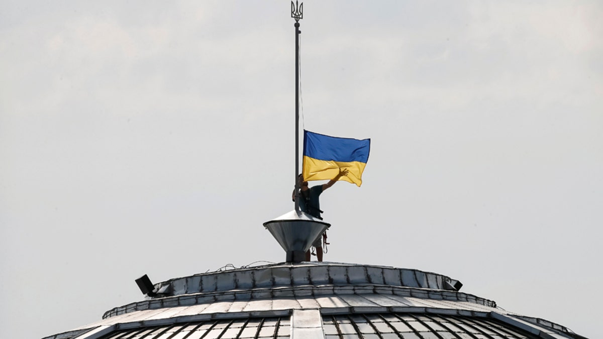 A climber installs the Ukrainian national flag on a roof, marking the Day of the State Flag, on the eve of the Independence Day, in Kiev, Ukraine, August 23, 2016. REUTERS/Gleb Garanich - RTX2MNGB