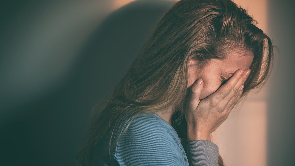 A woman sitting alone and depressed in sunset