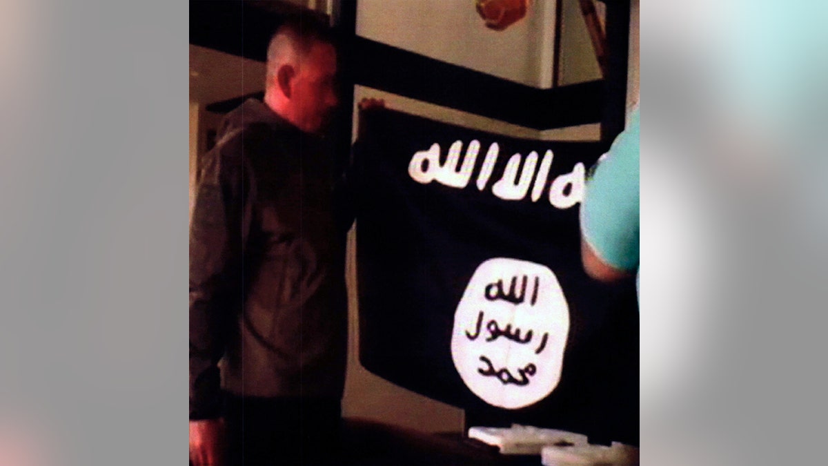 FILE - In this July 8, 2017 file image taken from FBI video and provided by the U.S. Attorney's Office in Hawaii on July 13, 2017, Army Sgt. 1st Class Ikaika Kang holds an Islamic State group flag after allegedly pledging allegiance to the terror group at a house in Honolulu. Newly unsealed court documents from an investigation into the Hawaii-based Army soldier accused of attempting to support the Islamic State group, provides more details about his obsession with the group's violence. (FBI/U.S Attorney's Office, District of Hawaii via AP, File)
