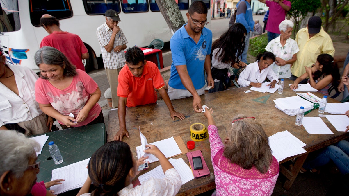 Voters register with members of the ruling United Socialist Party before proceeding to a polling post to vote in presidential elections in Valencia, Venezuela, Sunday, May 20, 2018. Known as 