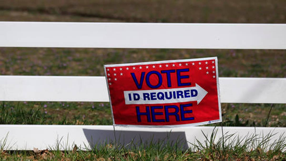 A sign directing voters is posted along a fence line at the Platte County Fair Grounds in Tracy, Mo., Tuesday, March 15, 2016. Voters in Missouri, as well as North Carolina, Illinois, Ohio and Florida are casting their ballots in primary elections Tuesday. (AP Photo/Orlin Wagner)