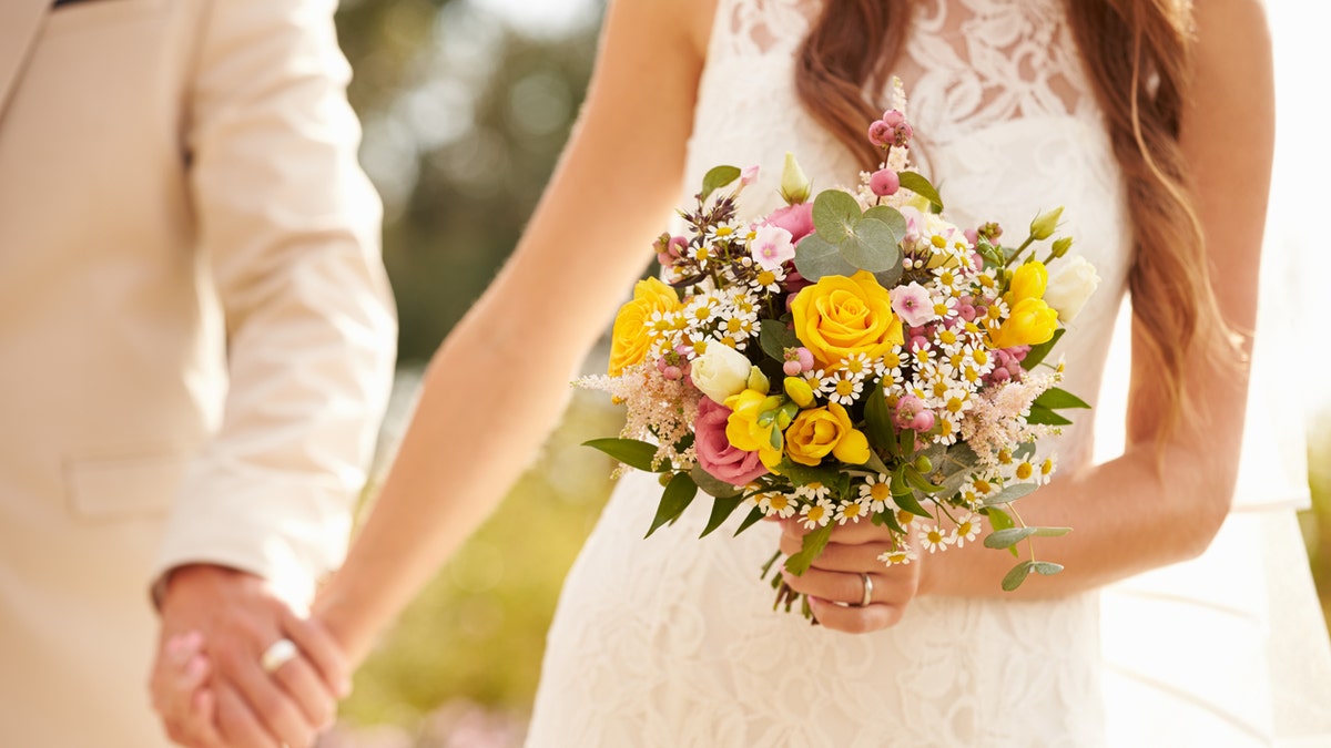 Close Up Of Couple At Wedding Holding Hands