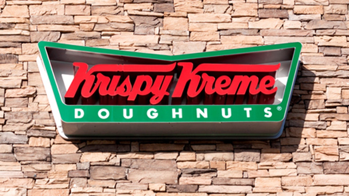 Chula Vista, USA - April 29, 2011: Red and green Krispy Kreme Doughnuts Sign as viewed from the sidewalk. The building exterior is made of stone with blue awnings for each store window. Krispy Kreme Doughnuts have been in business serving doughnuts and coffee since 1937. Krispy Kreme Doughnut stores operate in 14 countries around the globe.