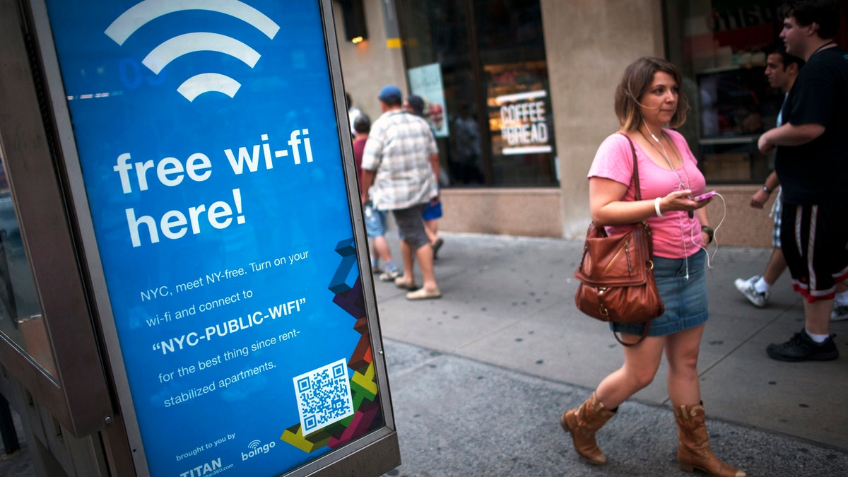 A woman walks past a WiFi-enabled phone booth in New York July 12, 2012. The New York City Department of Information Technology and Telecommunications have announced that they have converted 10 public pay phones into free WiFi hot spots as part of a pilot program to determine if it is possible to expand all city pay phones into a city-wide WiFi network. REUTERS/Keith Bedford (UNITED STATES - Tags: BUSINESS SOCIETY SCIENCE TECHNOLOGY TELECOMS) - RTR34VSH