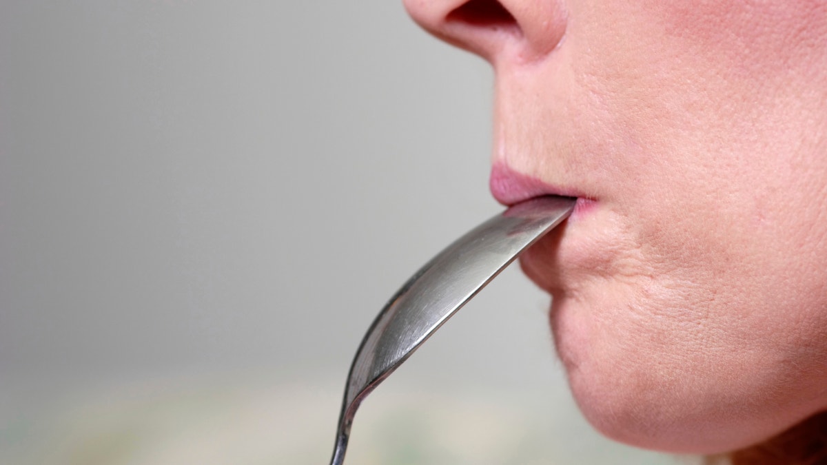 woman with spoon in mouth istock