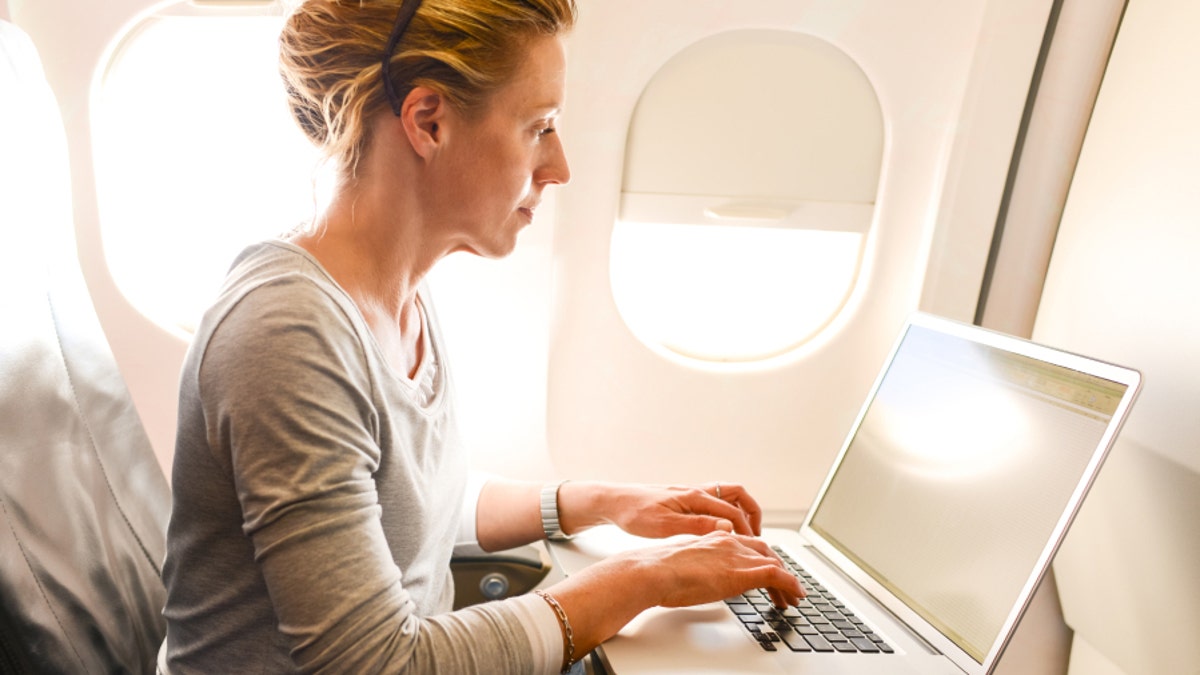 Woman Using Laptop in airplane during flight