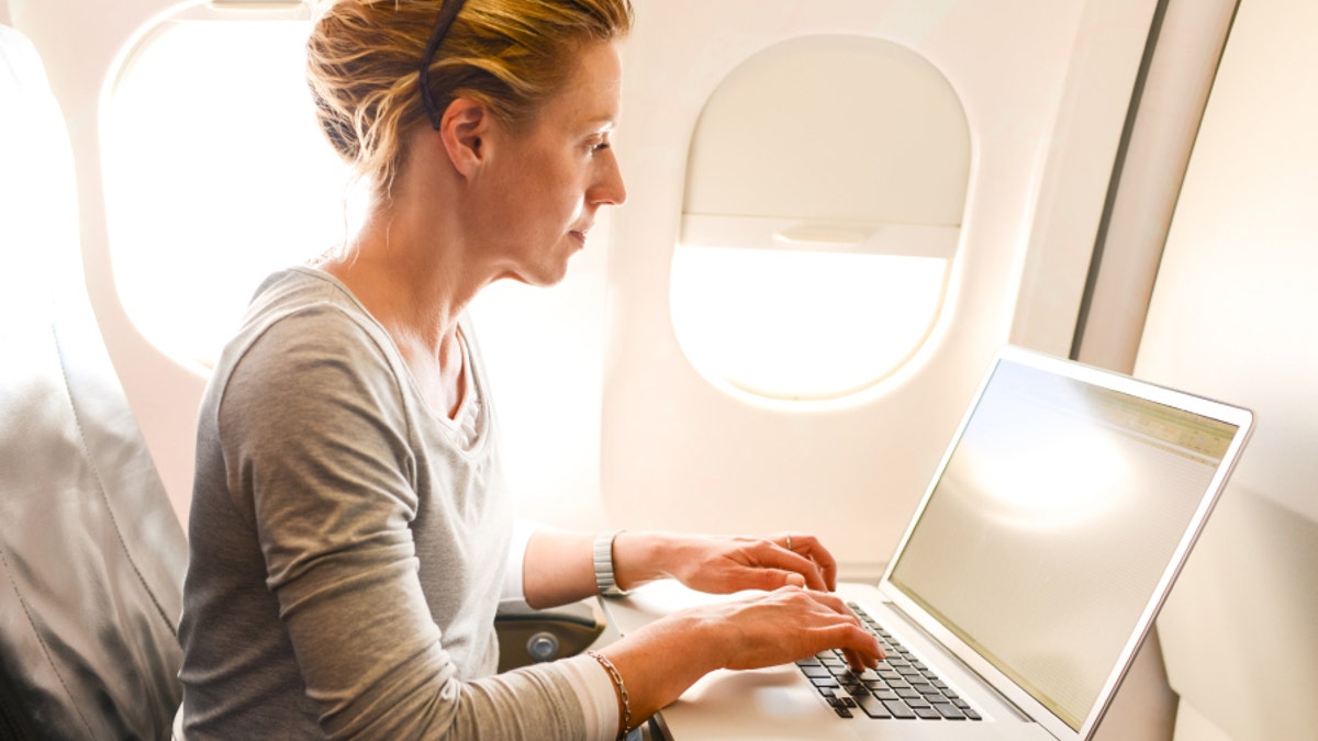 Woman Using Laptop in airplane during flight