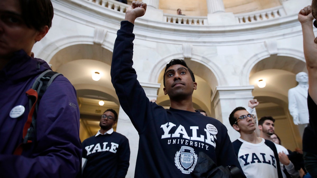 Yale student Jishian Ravinthiran, center, raises his fist during a protest against Judge Brett Kavanaugh in the Russell Senate Office Building Rotunda, on Capitol Hill, Monday, Sept. 24, 2018 in Washington. A second allegation of sexual misconduct has emerged against Judge Brett Kavanaugh, a development that has further imperiled his nomination to the Supreme Court, forced the White House and Senate Republicans onto the defensive and fueled calls from Democrats to postpone further action on his confirmation. President Donald Trump is so far standing by his nominee. (AP Photo/Alex Brandon)