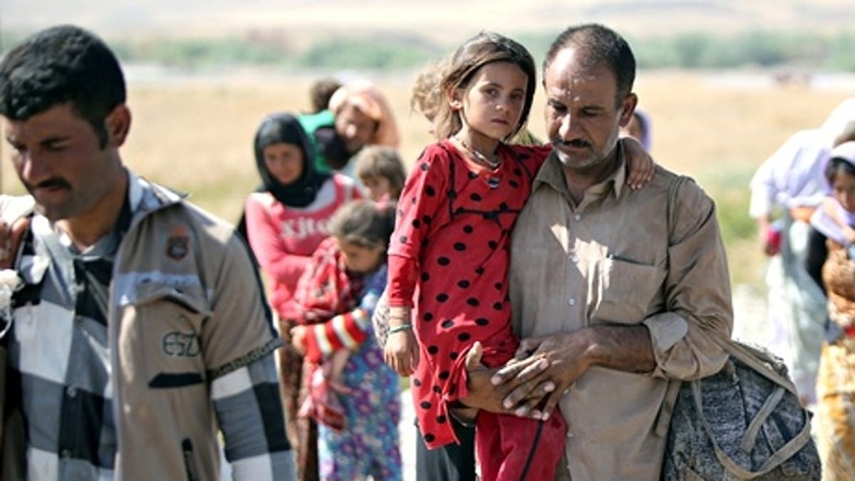 A displaced Yazidi Iraqi carries his daughter as they cross the Syrian border at Fishkhabour. Up to 20,000 people may still be trapped on Mount Sinjar. Photograph: Ahmad al-Rubaye/AFP/Getty