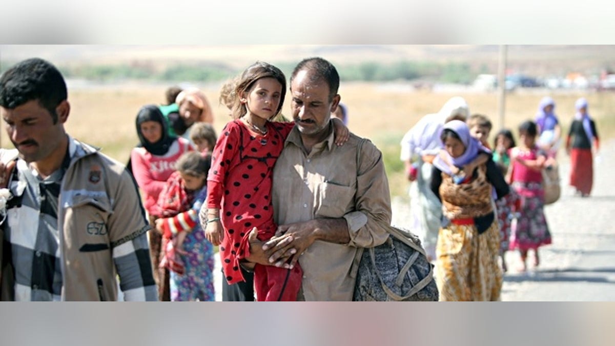 A displaced Yazidi Iraqi carries his daughter as they cross the Syrian border at Fishkhabour. Up to 20,000 people may still be trapped on Mount Sinjar. Photograph: Ahmad al-Rubaye/AFP/Getty