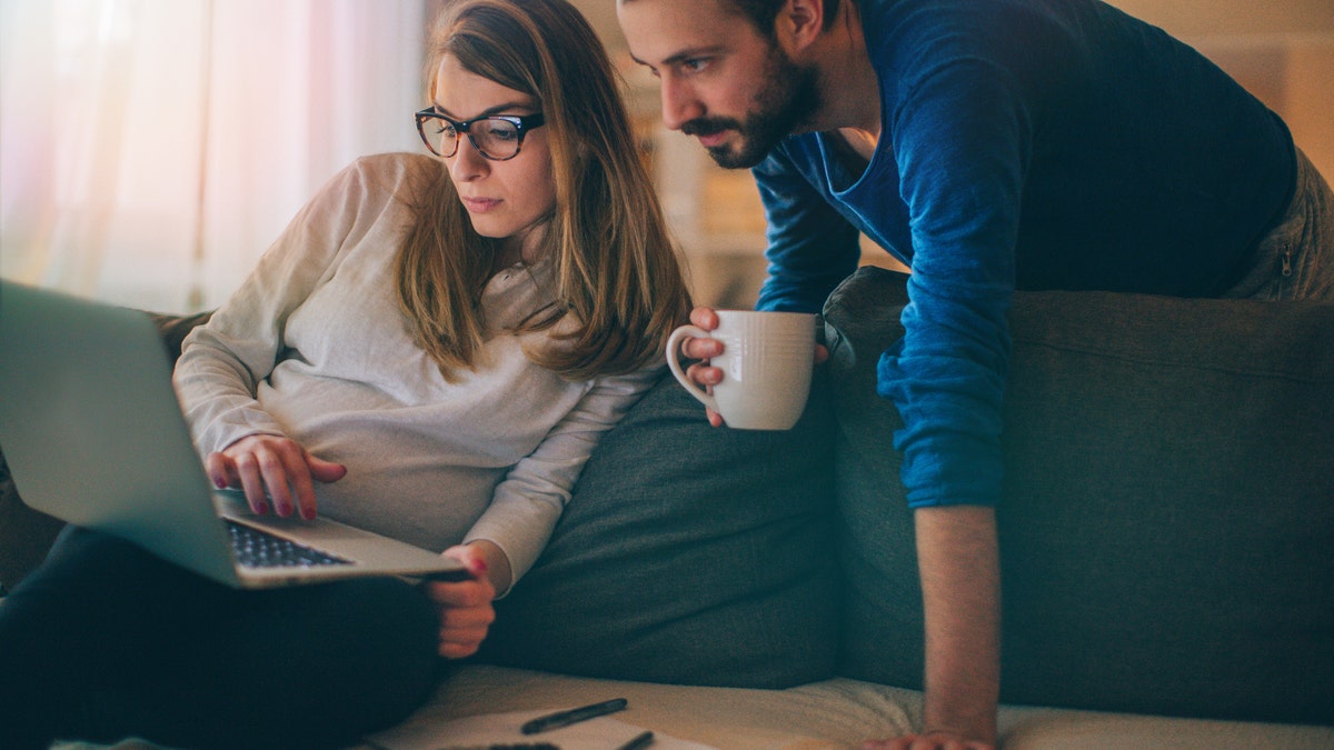 Couple sitting in their living room and checking their finances on the computer