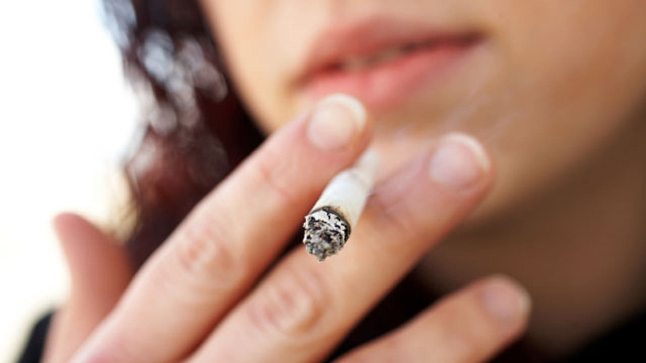 picture of person smoking a cigarette Young man smoking cigarette outdoors Stock Photo