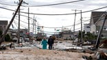 Robert Bryce, right, walkswith his wife, Marcia Bryce, through destruction from superstorm Sandy on Route 35 in Seaside Heights, N.J., Wednesday, Oct. 31, 2012. Sandy, the storm that made landfall Monday, caused multiple fatalities, halted mass transit and cut power to more than 6 million homes and businesses. (AP Photo/Julio Cortez)