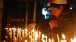 A Christian worshipper prays after lighting a candle on Christmas Eve at the Church of the Nativity, built atop the site where Christians believe Jesus Christ was born, in the West Bank City of Bethlehem, Saturday, Dec. 24, 2016. (AP Photo/Majdi Mohammed)