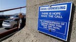 A sign is posted above a crisis counseling call box on the Golden Gate Bridge in San Francisco.