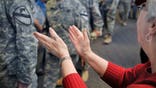 Troop Greeter Cathy Czarniecki claps her hands in applause for the passing troops returning from the mideast as they disembark at Bangor International Airport, Bangor, Maine, Tuesday, Nov. 10, 2009. (AP Photo/Michael C. York)