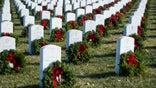 Wreaths rest against headstones at Arlington National Cemetery as Wreaths Across America places remembrance wreaths on headstones at the cemetery in Arlington, Va., Saturday, Dec. 16, 2017. (AP Photo/Cliff Owen)