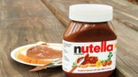 West Palm Beach, USA - October 27, 2011: Product shot of a container of Nutella hazelnut and cocoa spread. A saucer with a slice of bread freshly spread with a layer of Nutella is in the background.