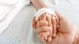 mother holding childs hand who fever patients have IV tube.