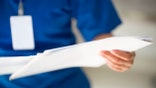 Unrecognizable nurse with medical report, selective focus