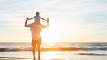 Happy Father and Son Having Fun Playing on the Beach at Sunset. Fatherhood Family Concept