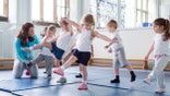 Nursery teacher helping one of her students during a physical education lesson.