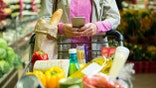 Woman using mobile phone while shopping in supermarket