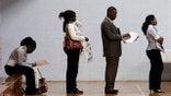 In this June 15 photo, job seekers wait in a line at a job fair in Southfield, Mich.