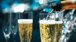Champagne being poured into champagne flutes, in a very sparkly, festive party.