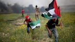 Palestinian demonstrators run during clashes with Israeli troops near the border with Israel, in the southern Gaza Strip March 23, 2018.