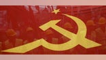 FILE - -People walk behind a red banner with hammer and sickle symbols during a May Day rally in Istanbul, Turkey, May 1, 2016.
