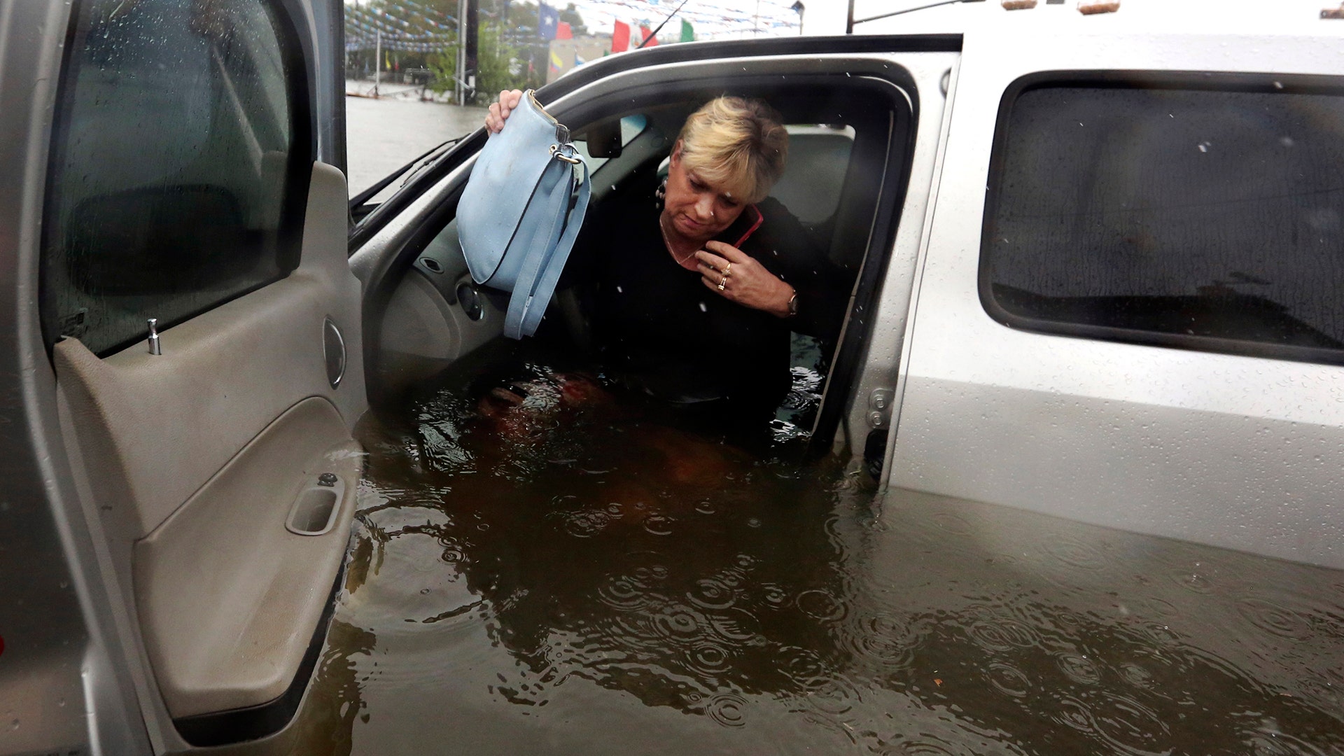 Rhonda Worthington talks on her cell phone with a 911 dispatcher after her vehicle stalled in rising floodwaters in Houston, Monday