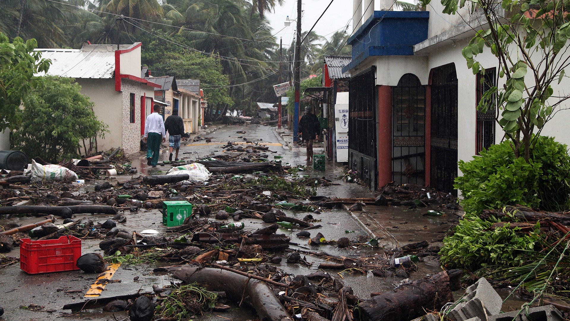 People walk on a street covered in debris from Hurricane Irma in Nagua, Dominican Republic, Thursday
