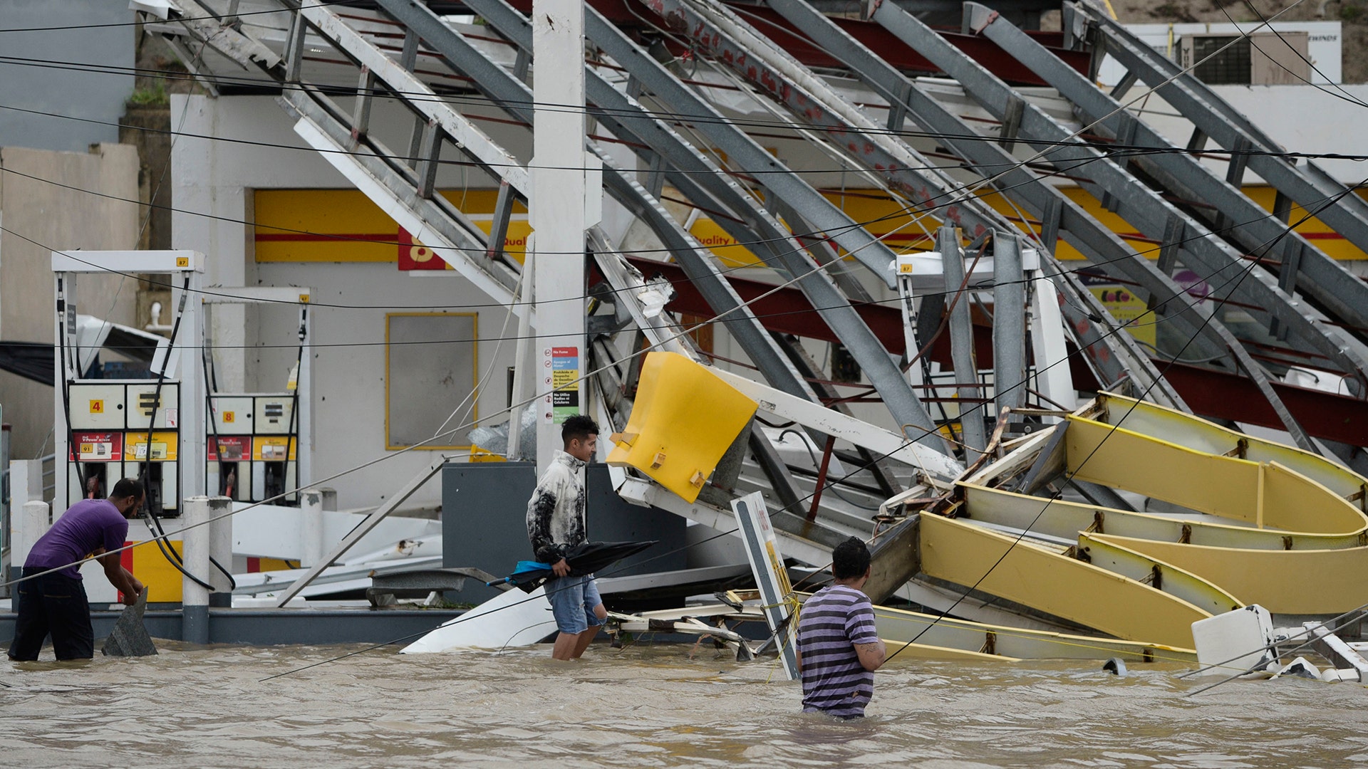People walk next to a gas station flooded and damaged by the impact of Hurricane Maria, in Humacao, Puerto Rico, Wednesday