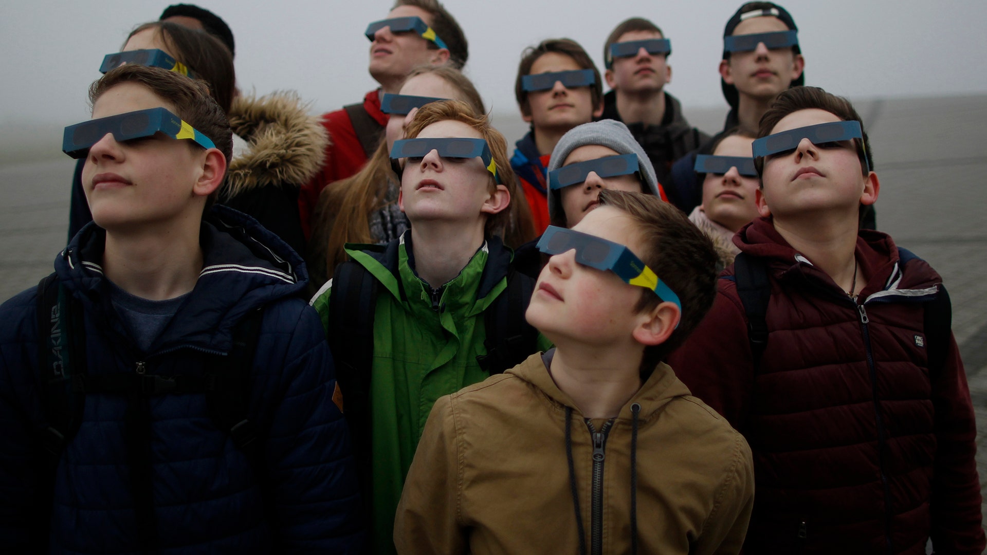 Students try to view a partial solar eclipse through thick fog at 'Halde Hoheward' in Herten, Germany,  March 20, 2015