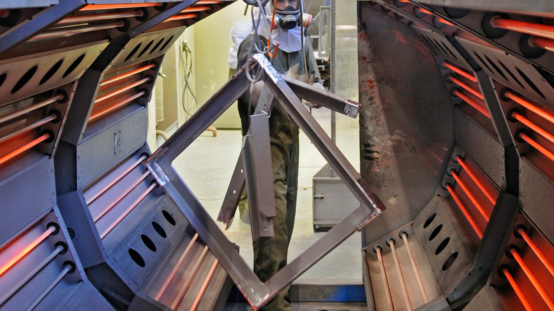 Painter/blaster Christopher Fuller removes a metal frame from the oven in preparation for powder coating  in the sandblast facility