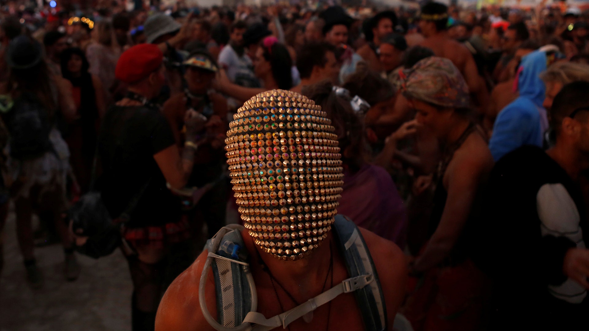 A participant wears a mask as he dances at the annual Burning Man arts and music festival in the Black Rock Desert of Nevada, August 29
