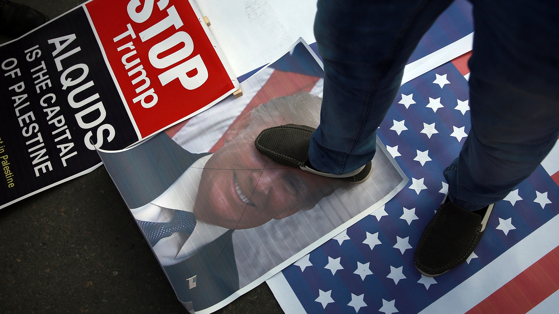 A Palestinian steps on a poster of U.S. President Donald Trump and a representation of the American flag  in Gaza City, December 7