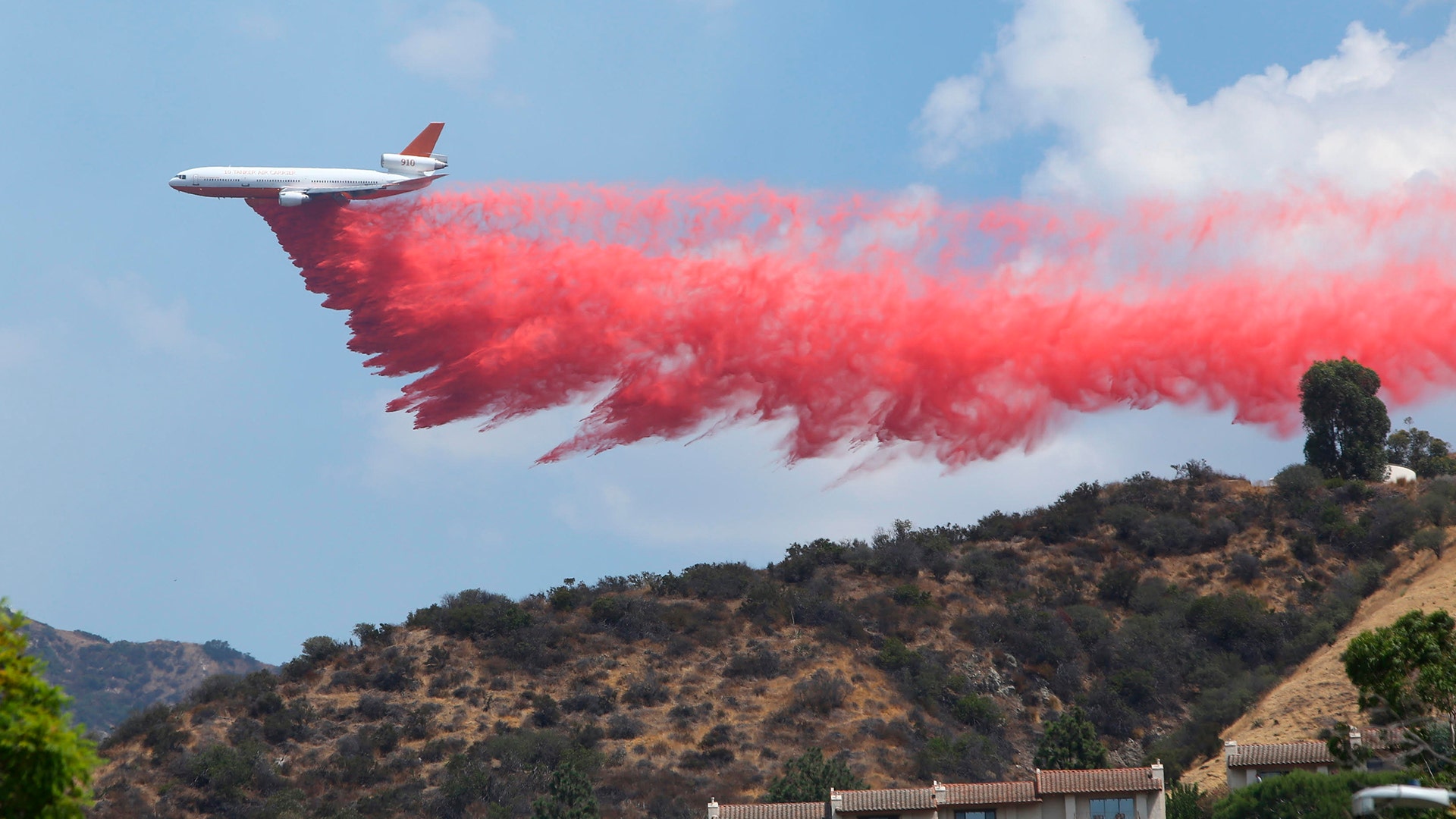 A DC-10 Tanker drops Phos-Chek retardant across a ridge while fighting the 