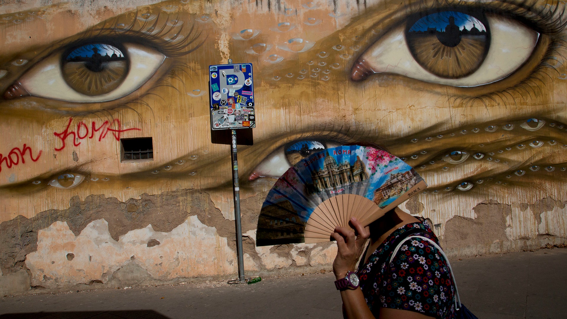 A woman walks past a mural by British street artist My Dog Sighs in Rome's Trastevere neighborhood, September 24, 2018