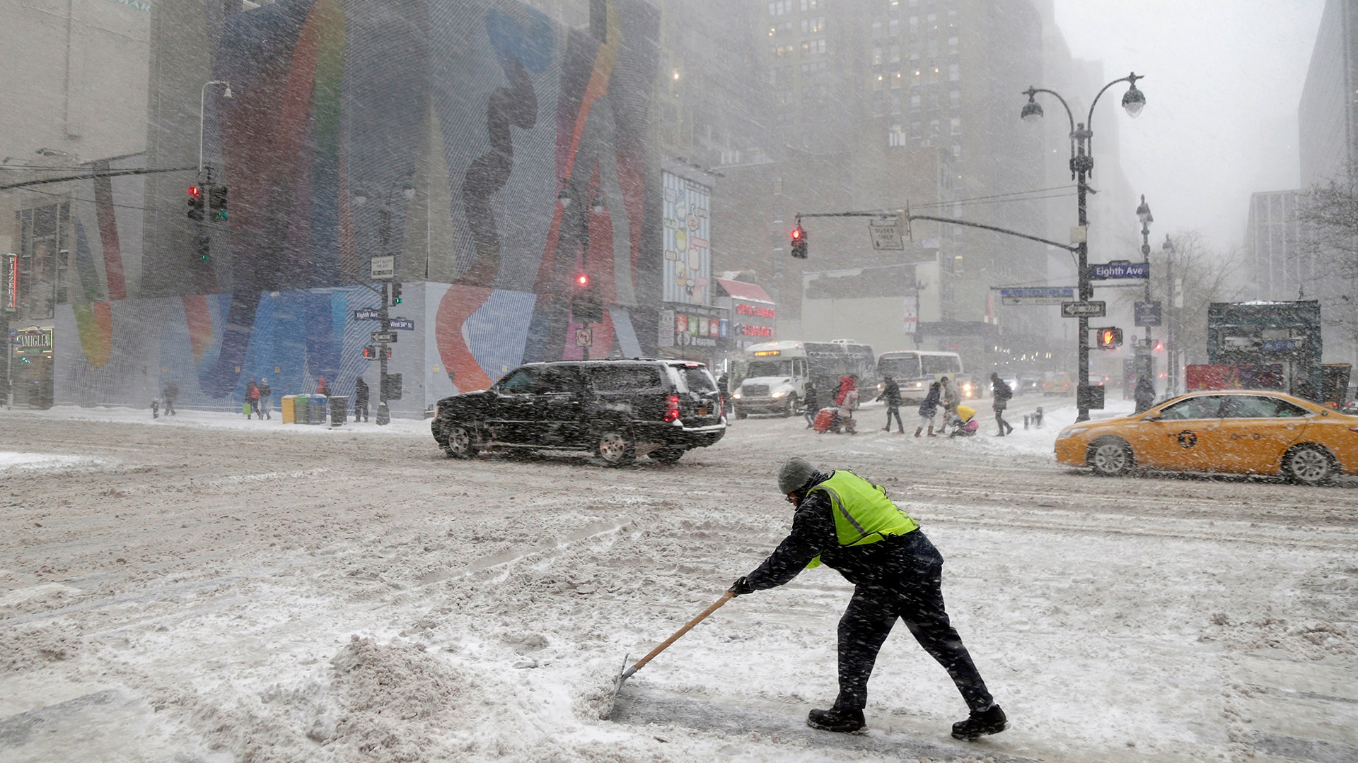 A man tries to clear snow at the intersection of Eighth Ave. and 34th St. in New York City, Thursday