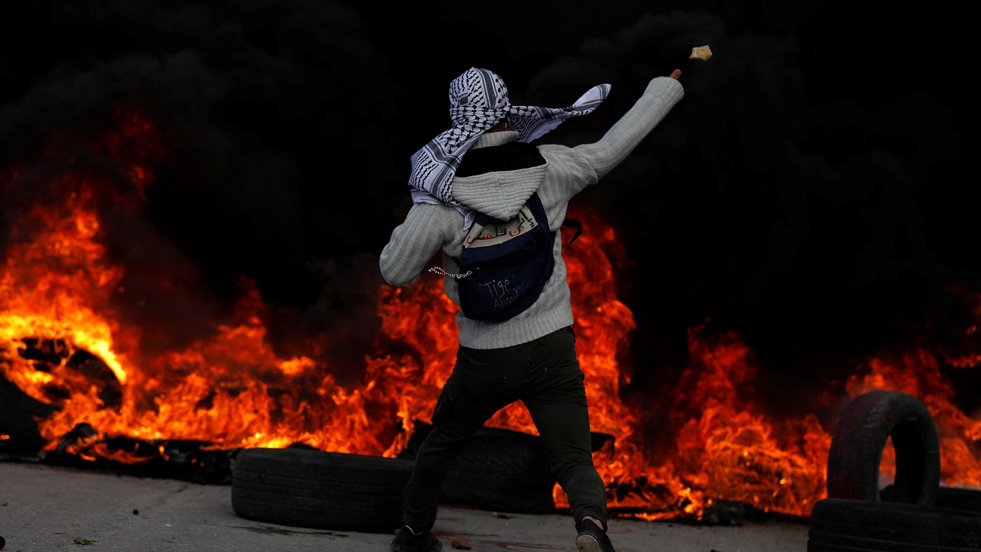 A Palestinian protester hurls stones towards Israeli troops during a protest against U.S. President Donald Trump in Ramallah, December 7