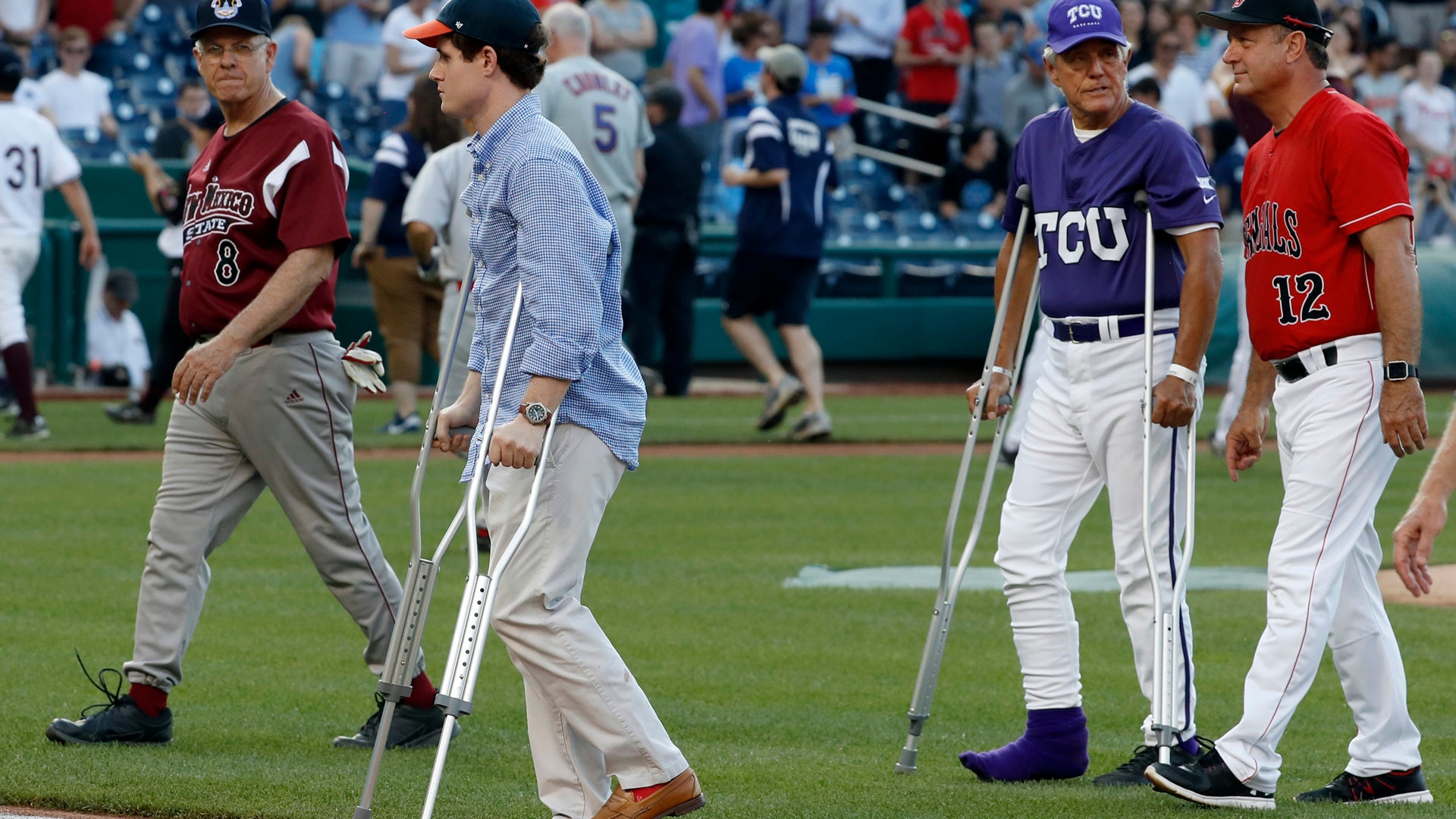 Injured aide Zach Barth, left, and Rep. Roger Williams, R-Texas, also on crutches walk off the field before the Congressional baseball game 