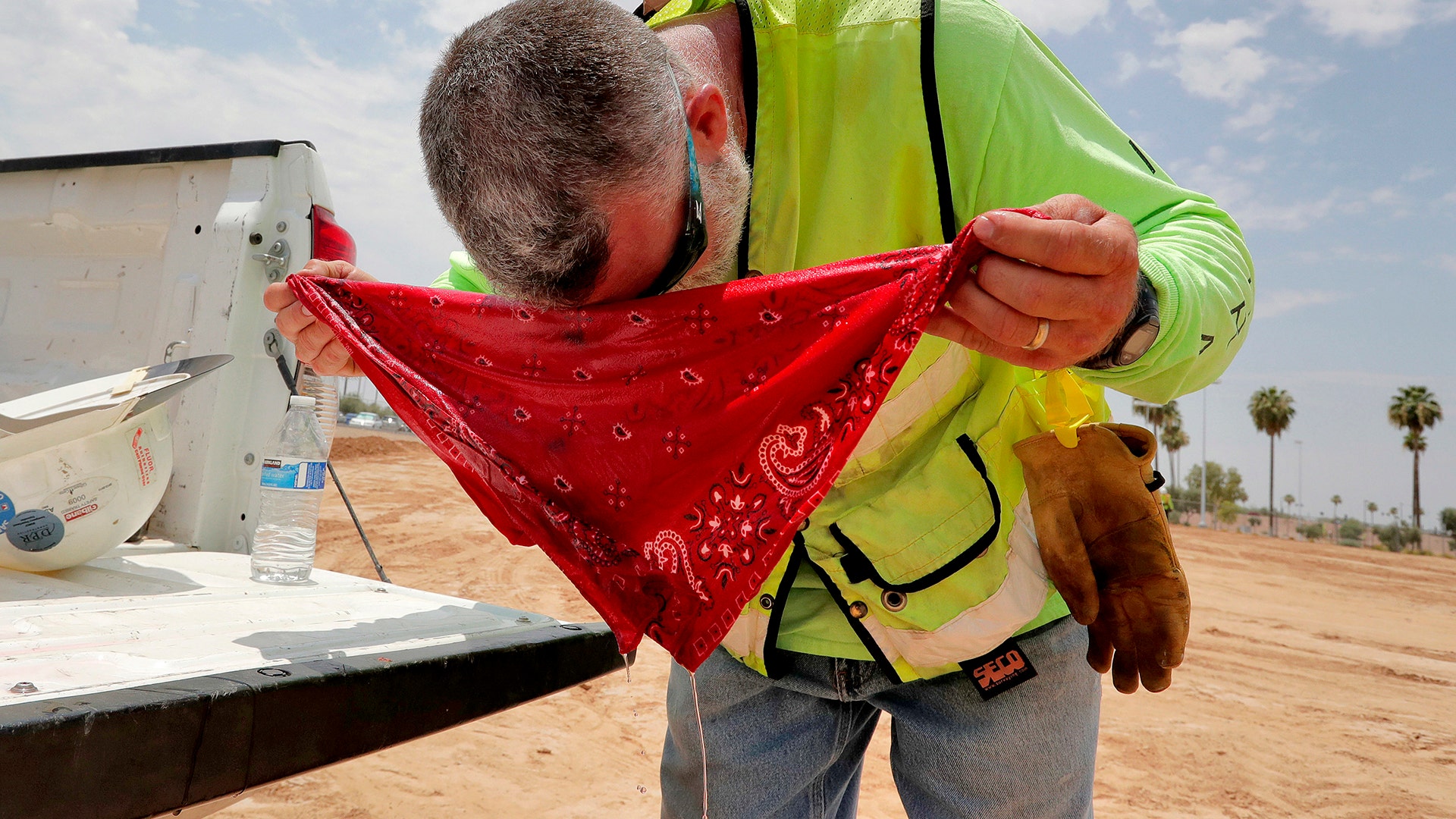 Dana Wheeler, a civil engineer with Integra Engineering, wraps a wet headband around his head to combat the heat in Tempe, Tuesday