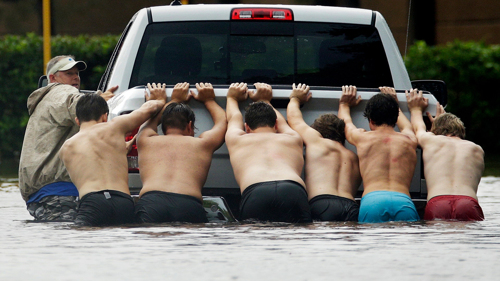 People push a stalled pickup to through a flooded street in Houston, after Tropical Storm Harvey dumped heavy rains Sunday