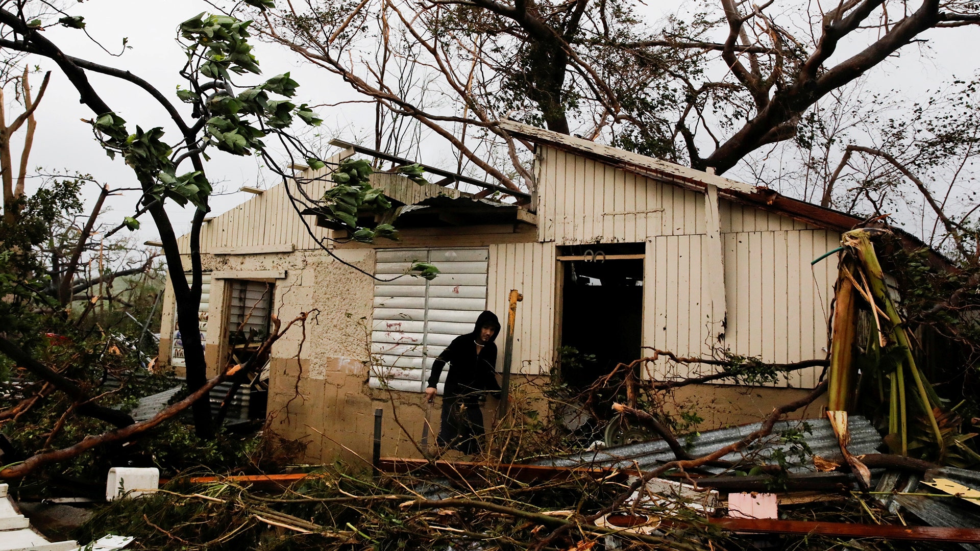 A man looks for valuables in the damaged house of a relative after the area was hit by Hurricane Maria in Guayama, Puerto Rico, Wednesday